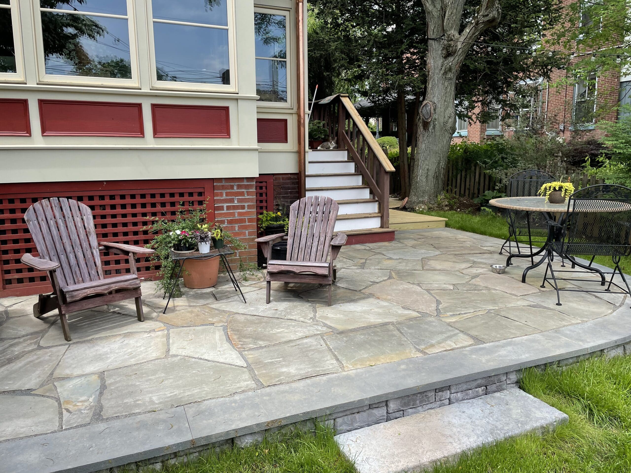 Newly renovated patio by CKC Landscaping with a pergola, featuring brick pavers and a set of stairs leading to a garden.