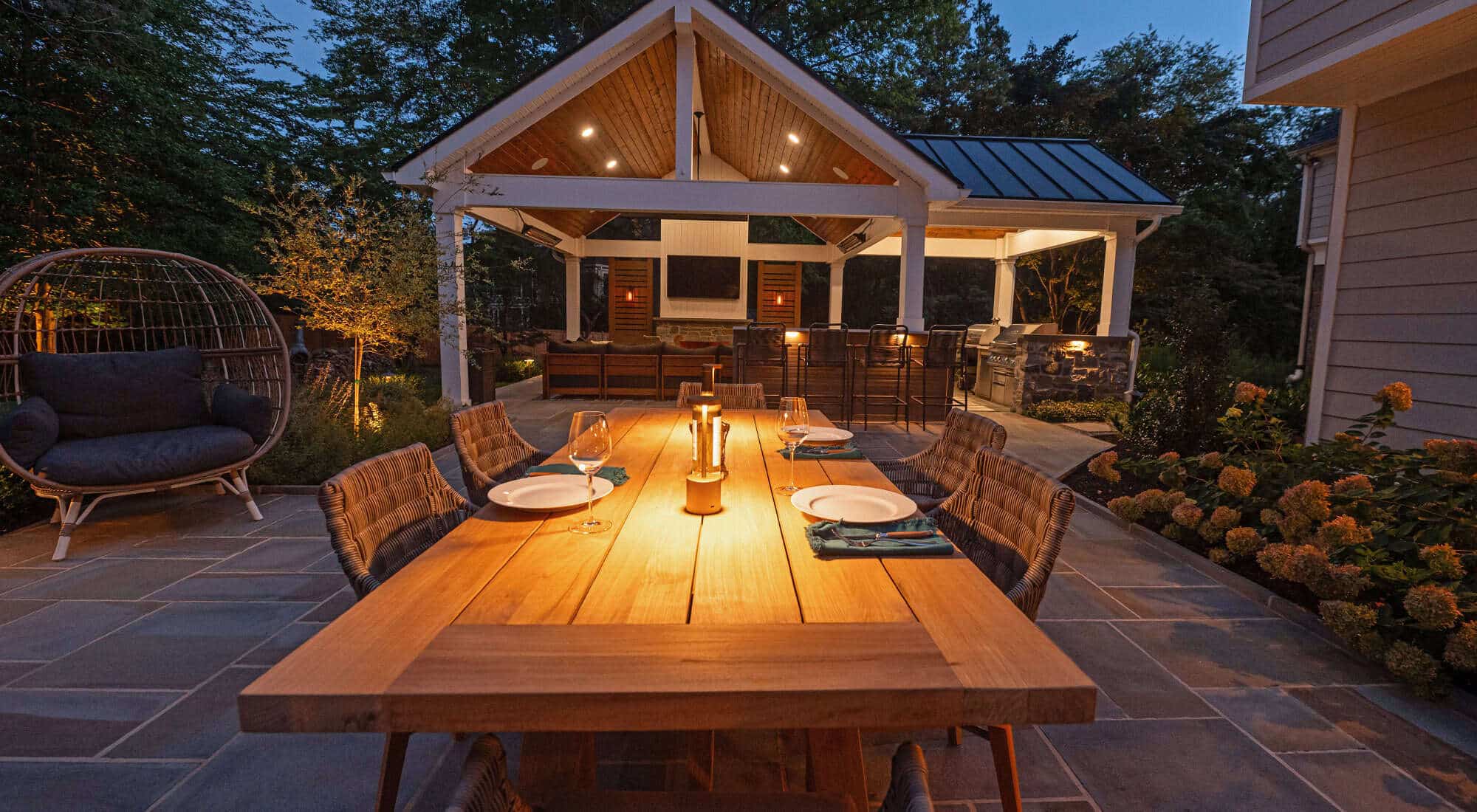 Night view of wet laid flagstone patio with outdoor kitchen and roof structure in Chester County