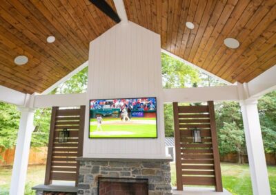 Outdoor TV mounted on stone fireplace showing Phillies baseball game in West Chester