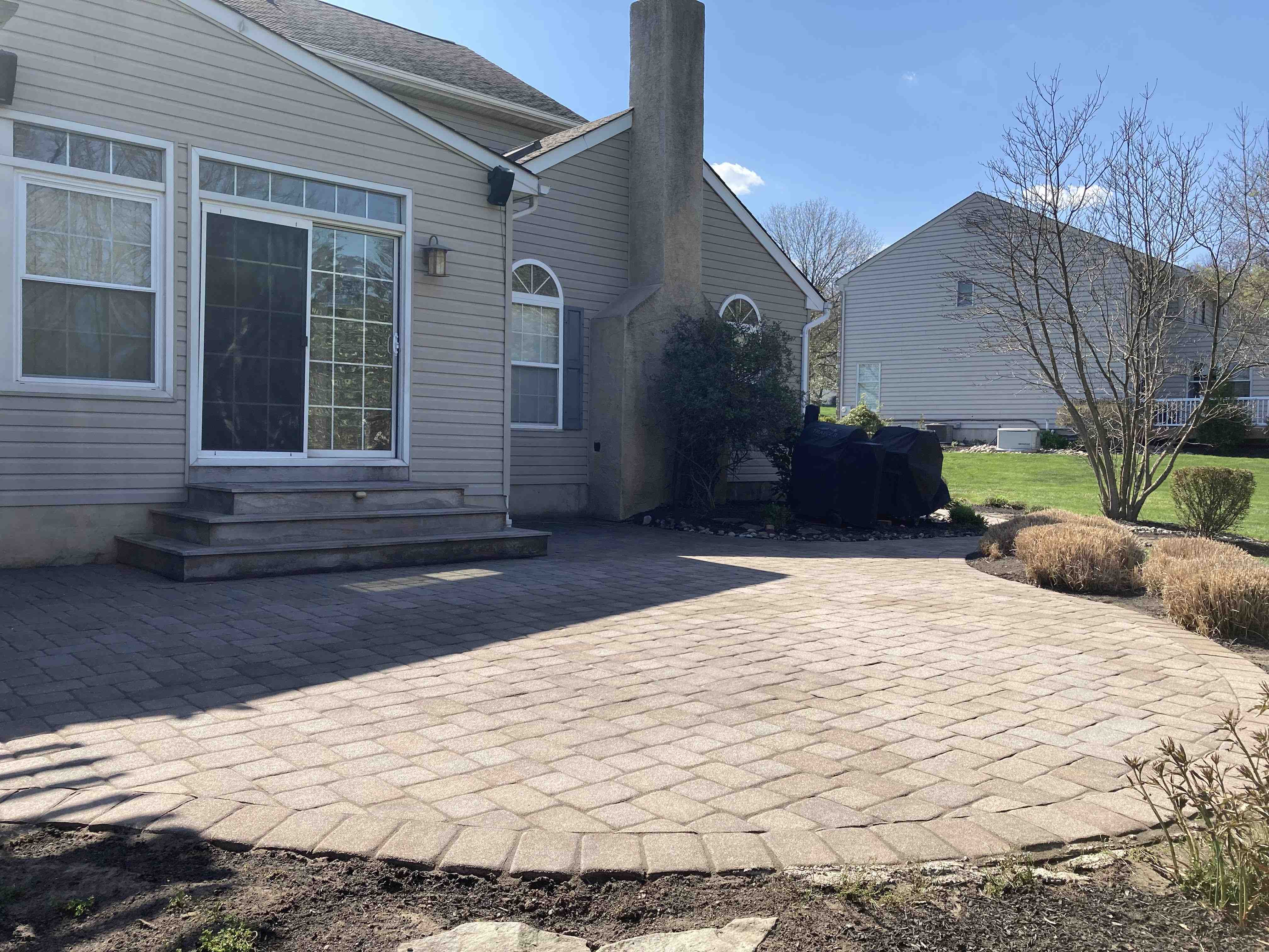 Before and after paver patio cleaning and sealing restoration in West Chester PA showing moss removal and joint sand replacement.
