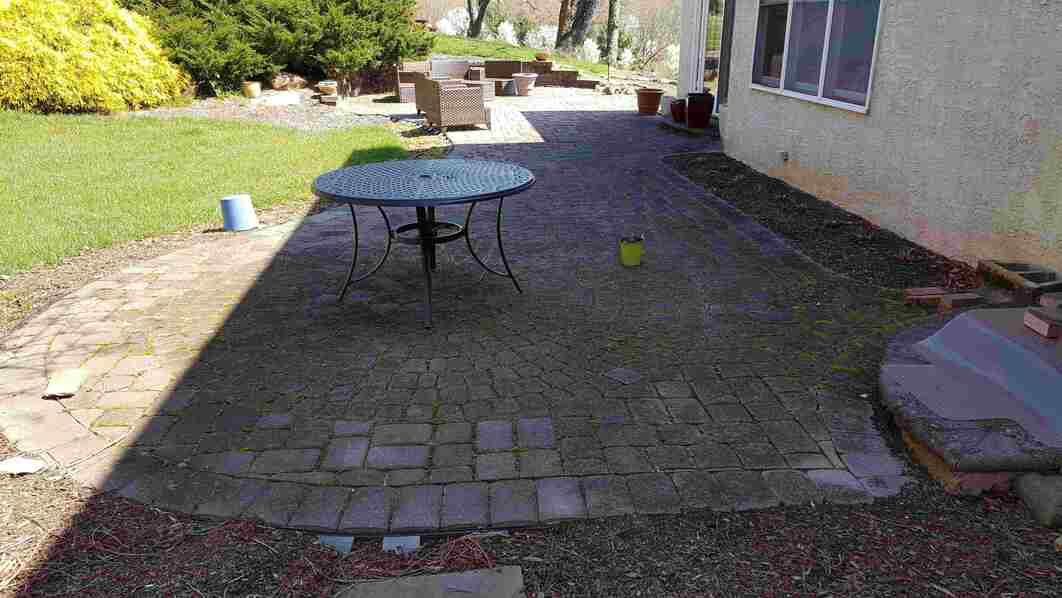 Before paver patio restoration and enhancement in West Chester PA showing moss removal and joint sand replacement.