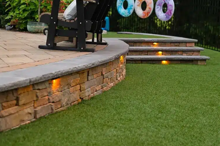 Artificial turf and Belgard Cast Stone Wall 7 Natural stone retaining wall with artificial turf for backyard erosion control and zero maintenance.
